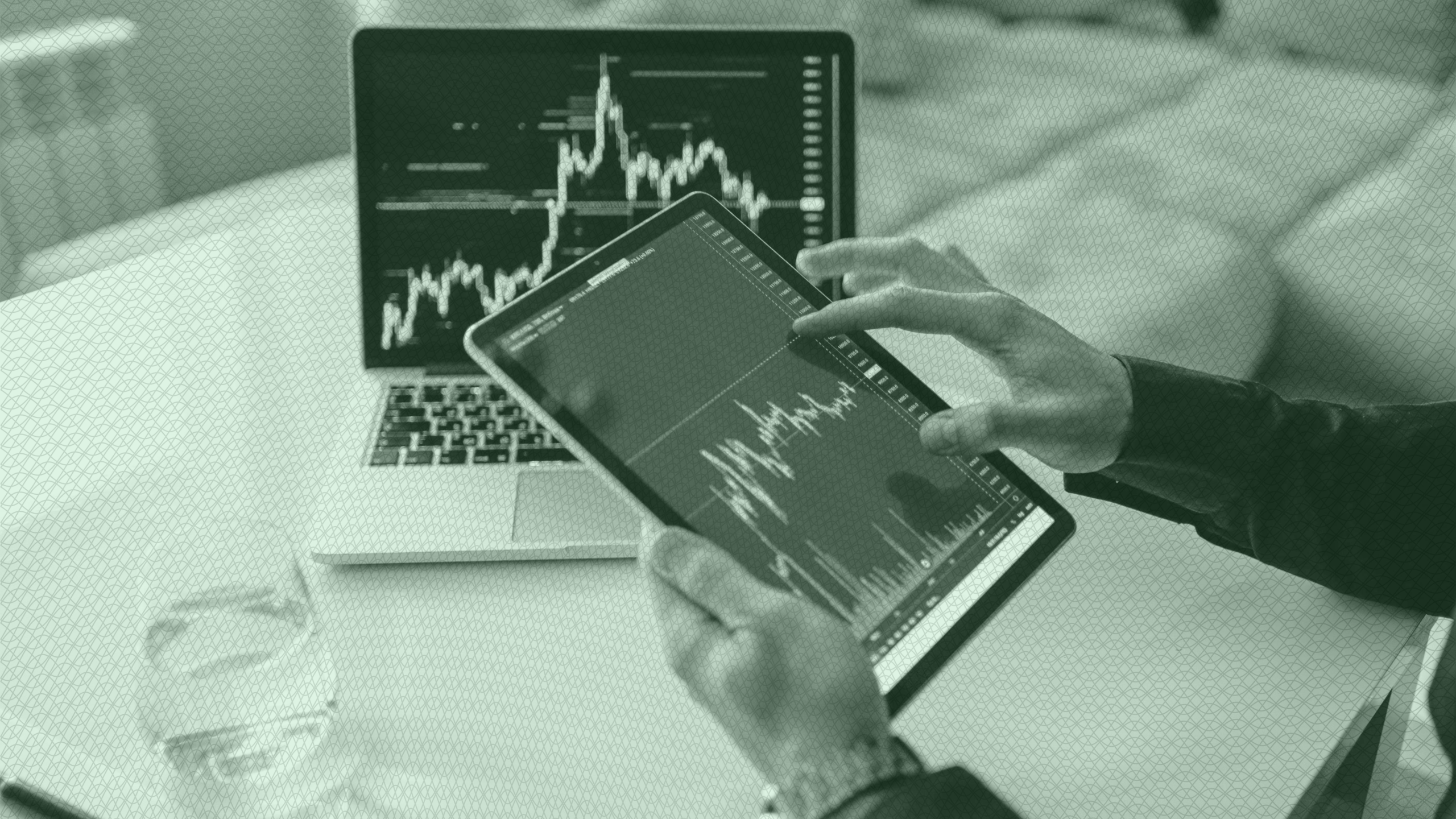 Photo of a person looking at stock charts on a tablet and laptop