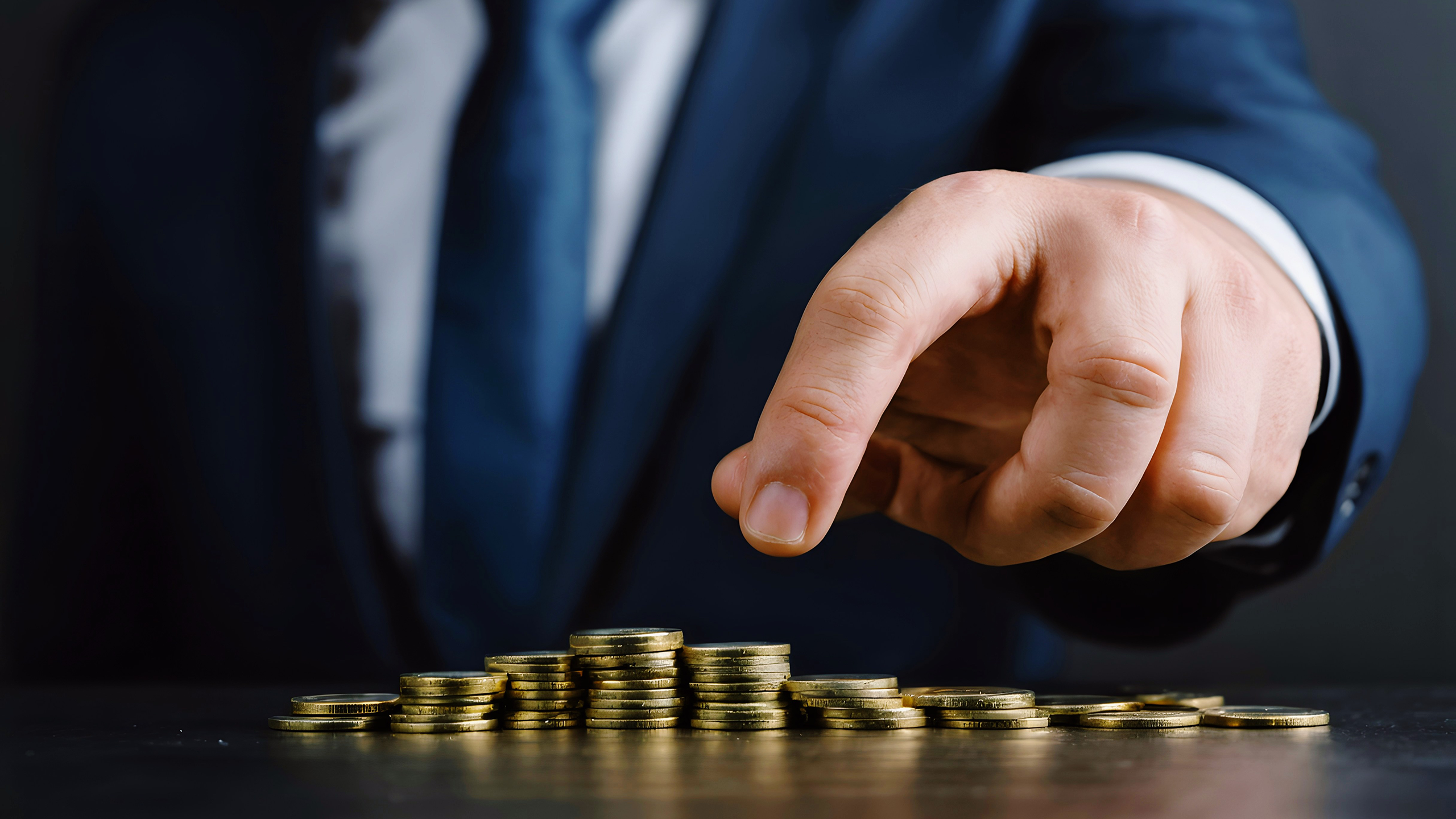 Photo of a man in a suit counting gold coins