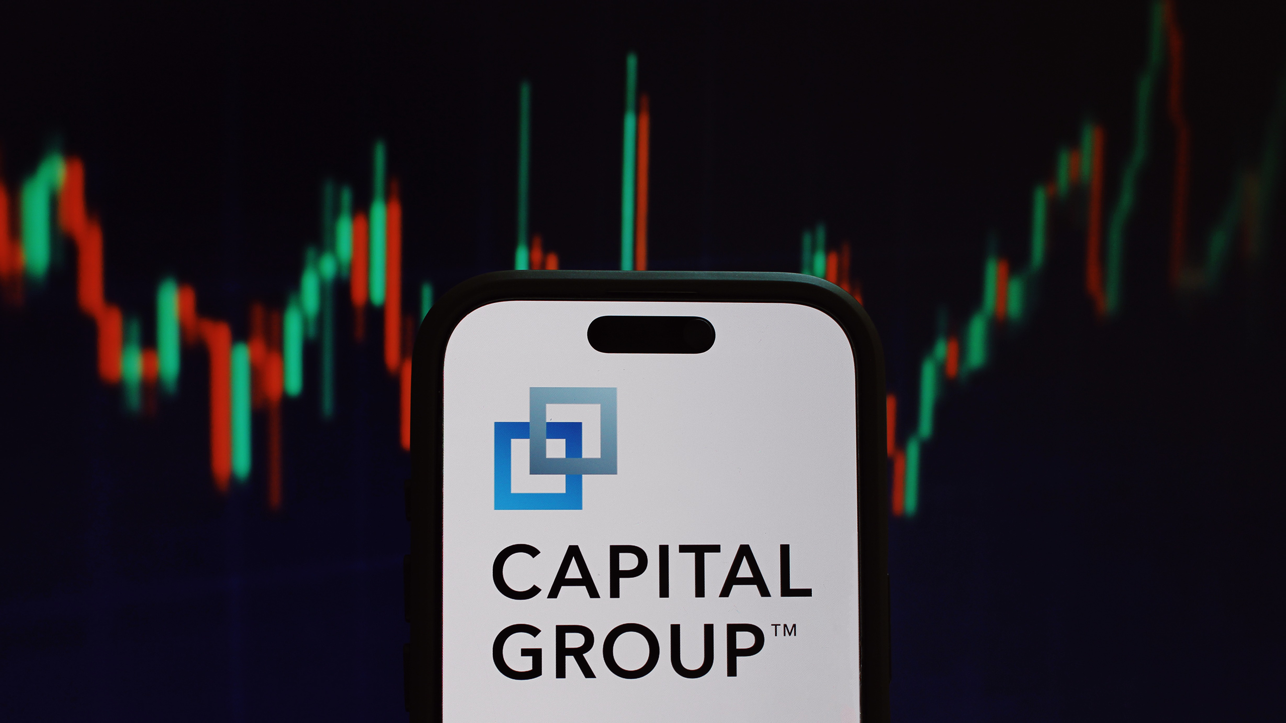 Photo of the Capital Group logo in front of stock charts
