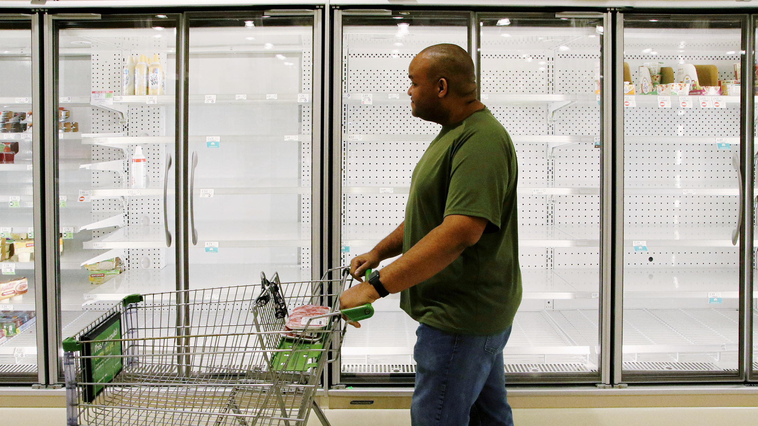 Photo of a person looking at empty shelves in a grocery store