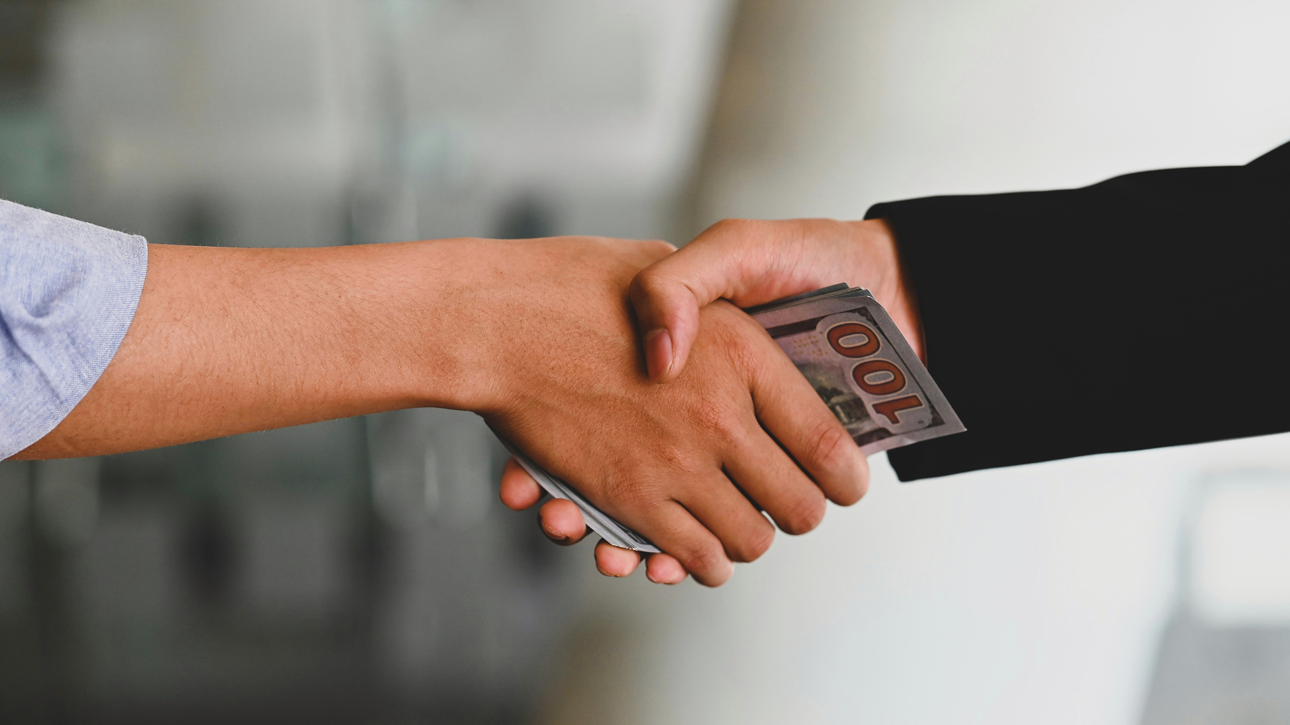 Photo of a person handing over money in a handshake