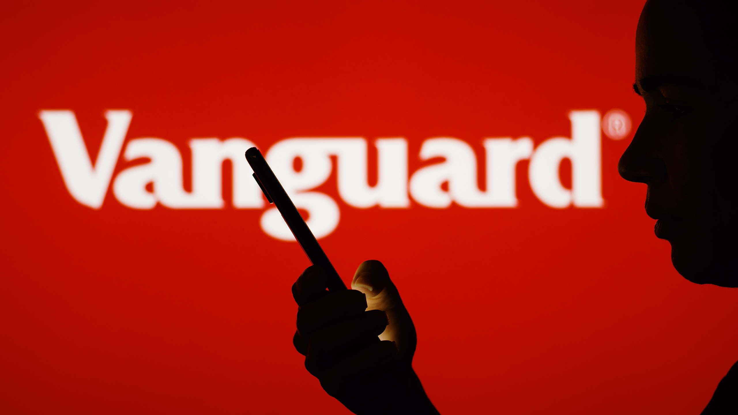 Photo of a person using a phone in front of a Vanguard sign