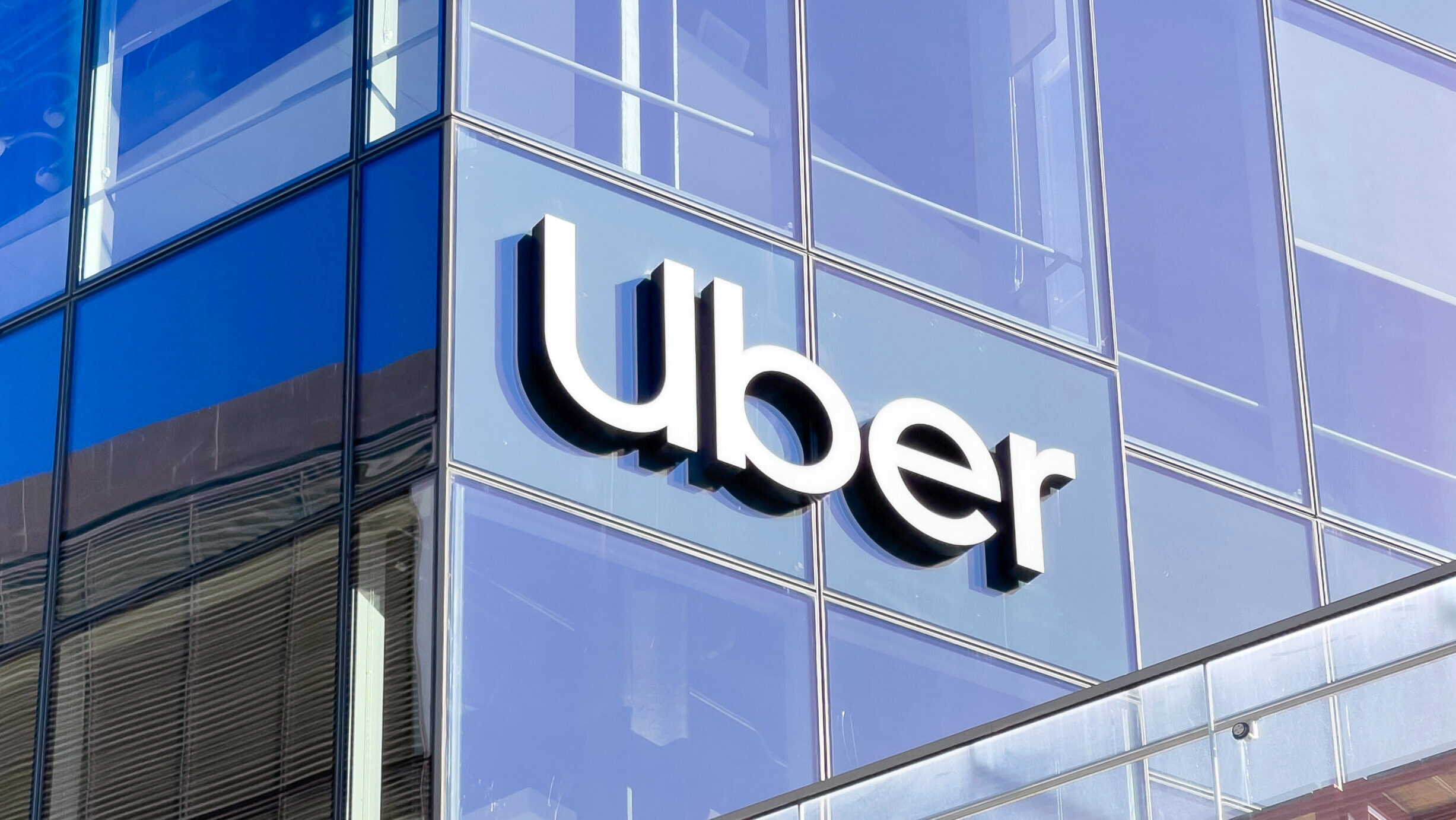 The Uber logo is shown on a glass window at the company's San Francisco headquarters.