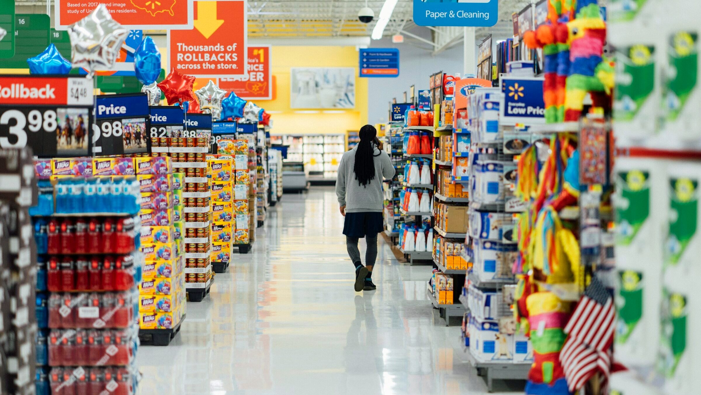 A shopper walks between the aisles of a major department store stocked with goods.