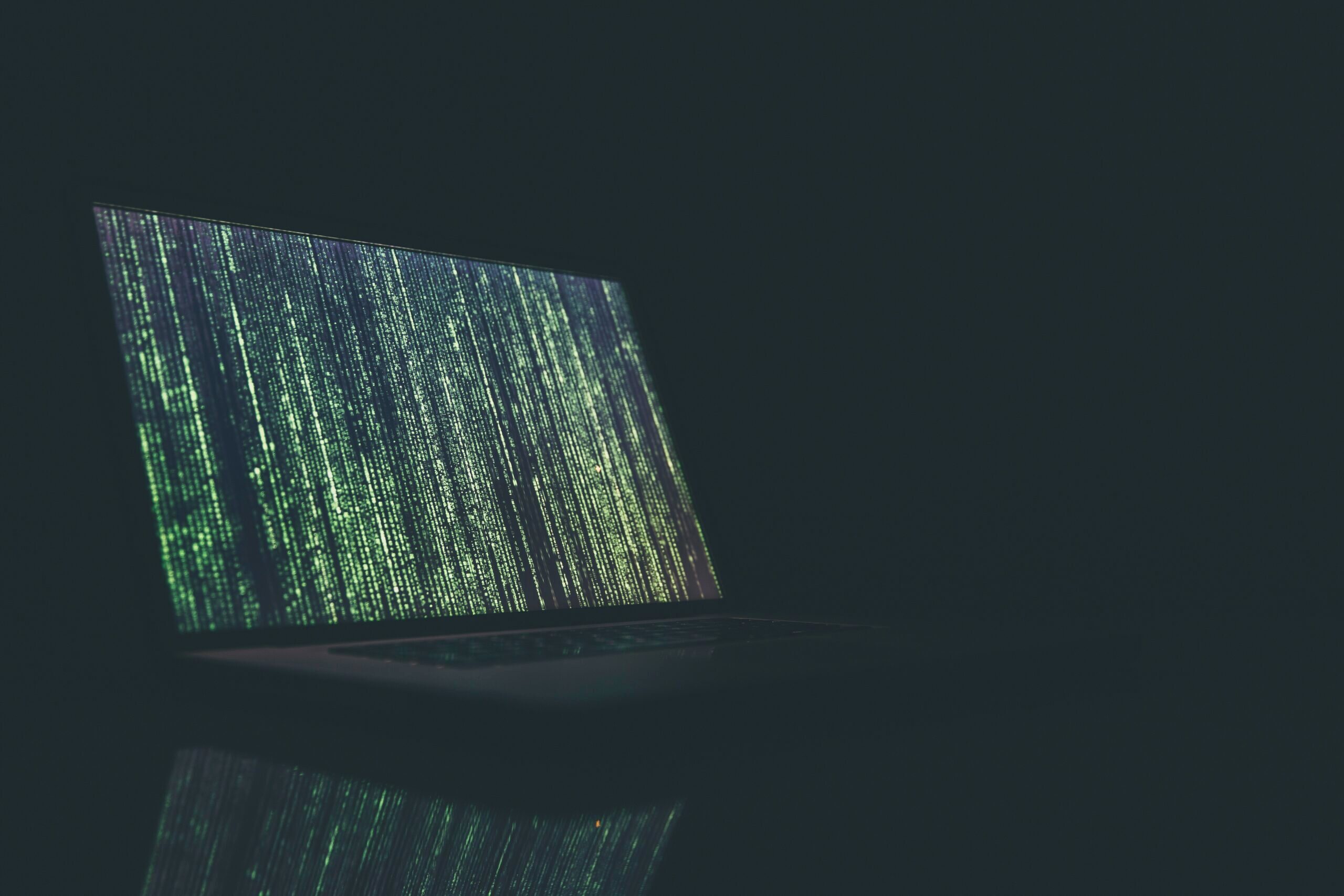 Photo of code on a computer screen in a dark room.