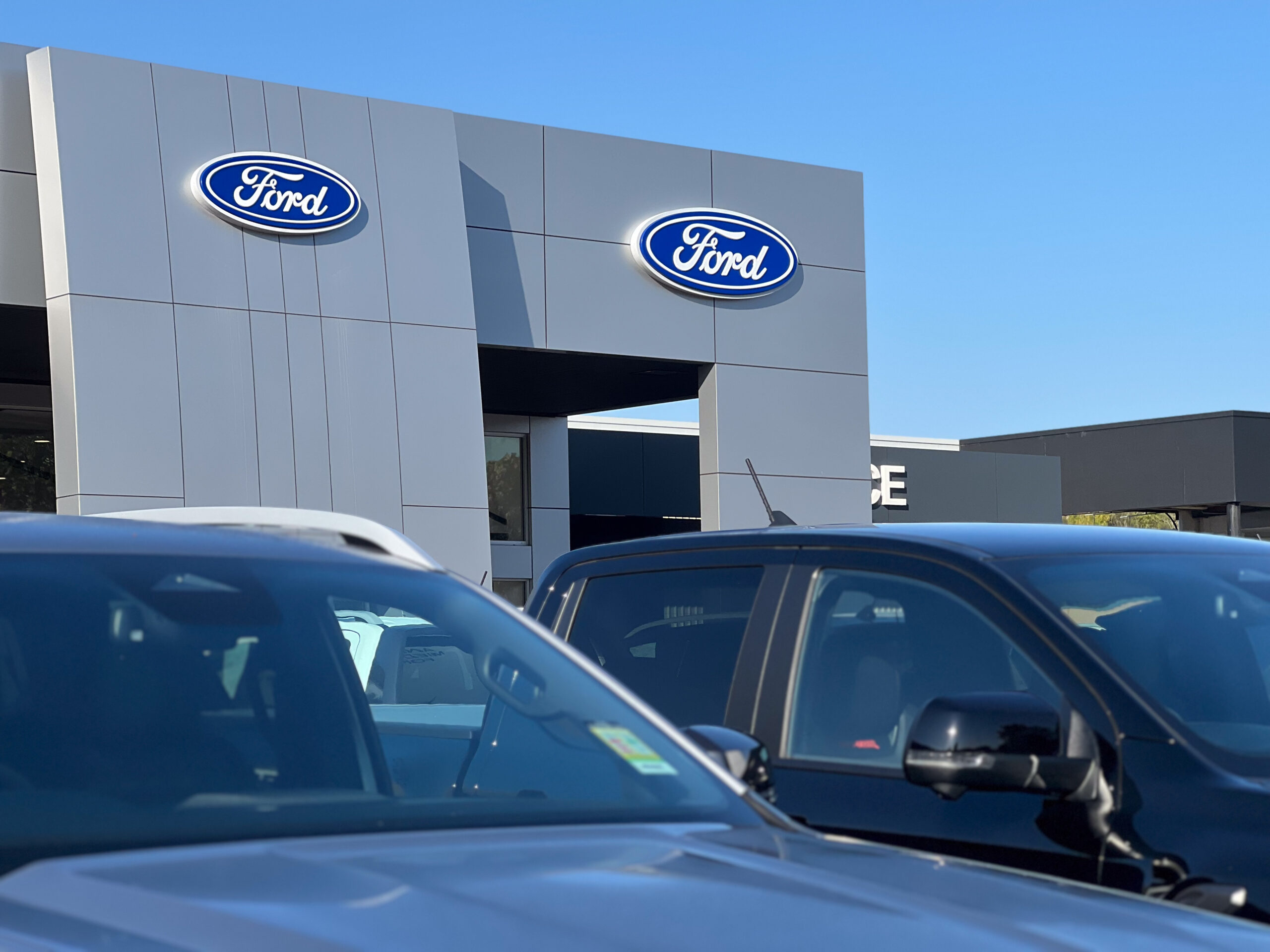 Vehicles sit in front of a Ford dealership.