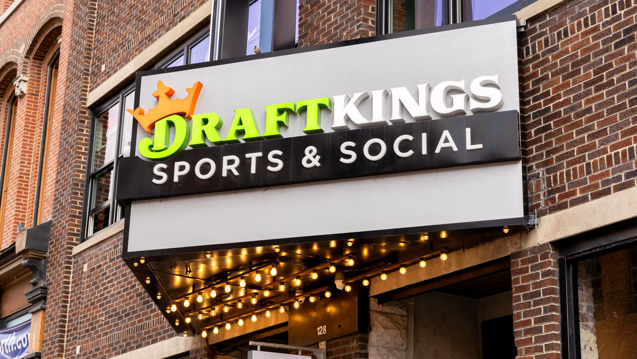 A DraftKings Sports and Social location in Nashville, viewed from outdoors, bears the company's logo on a marquee display.