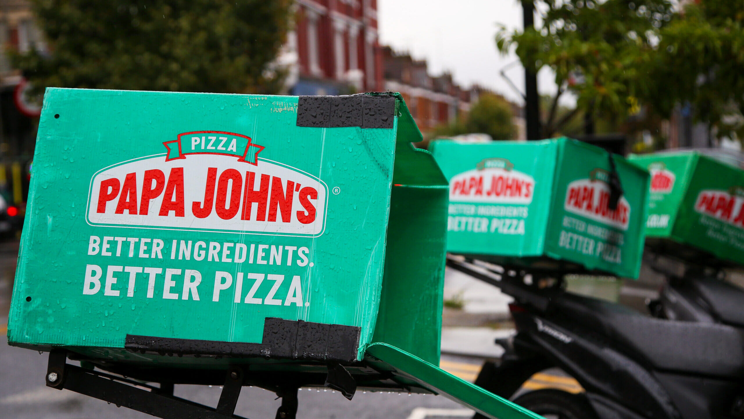Photo of a row of parked Papa John's pizza delivery bikes.
