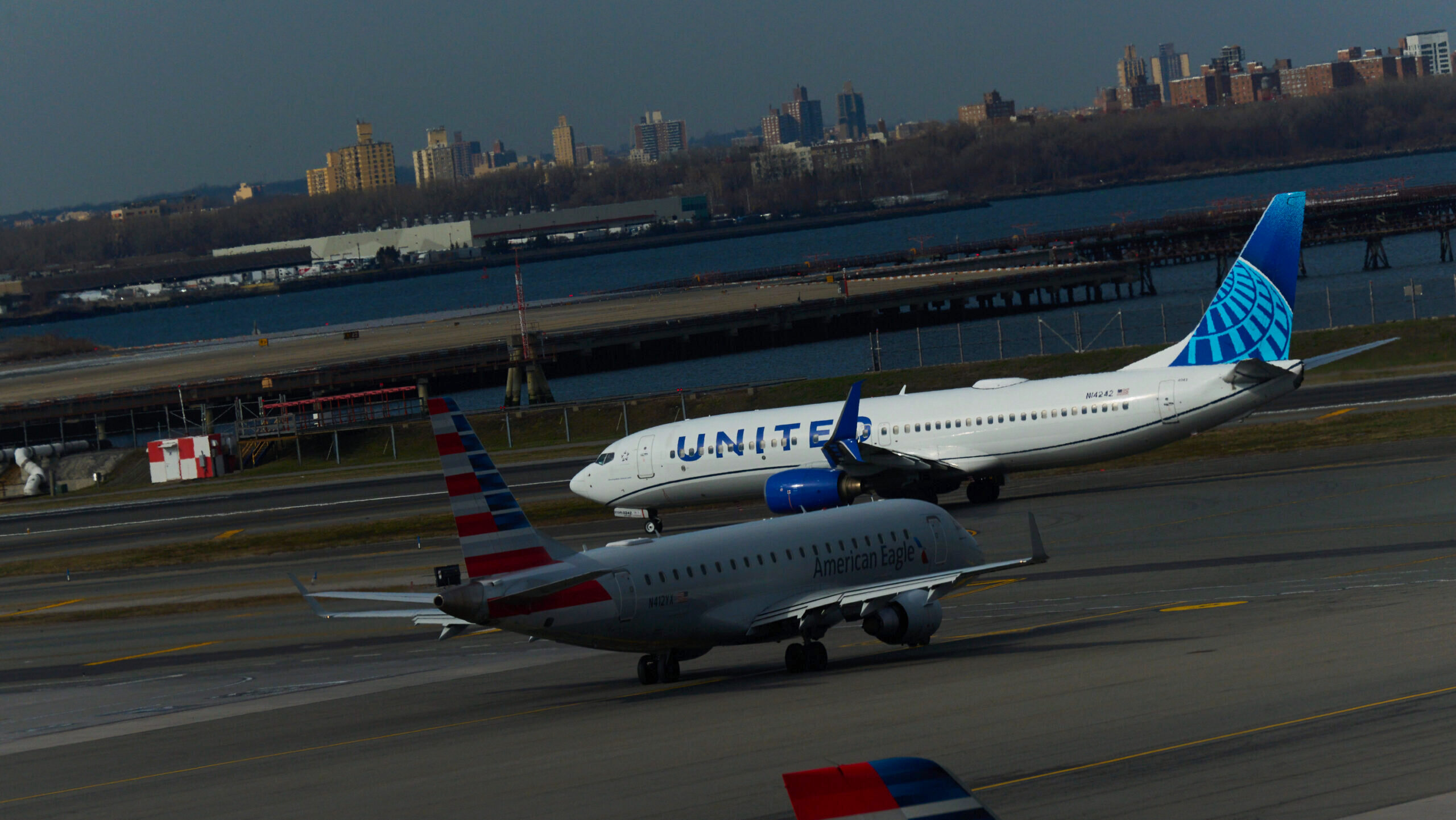 A United Airlines and American Airlines jet taxi towards the runway of LaGuardia Airport in New York City.