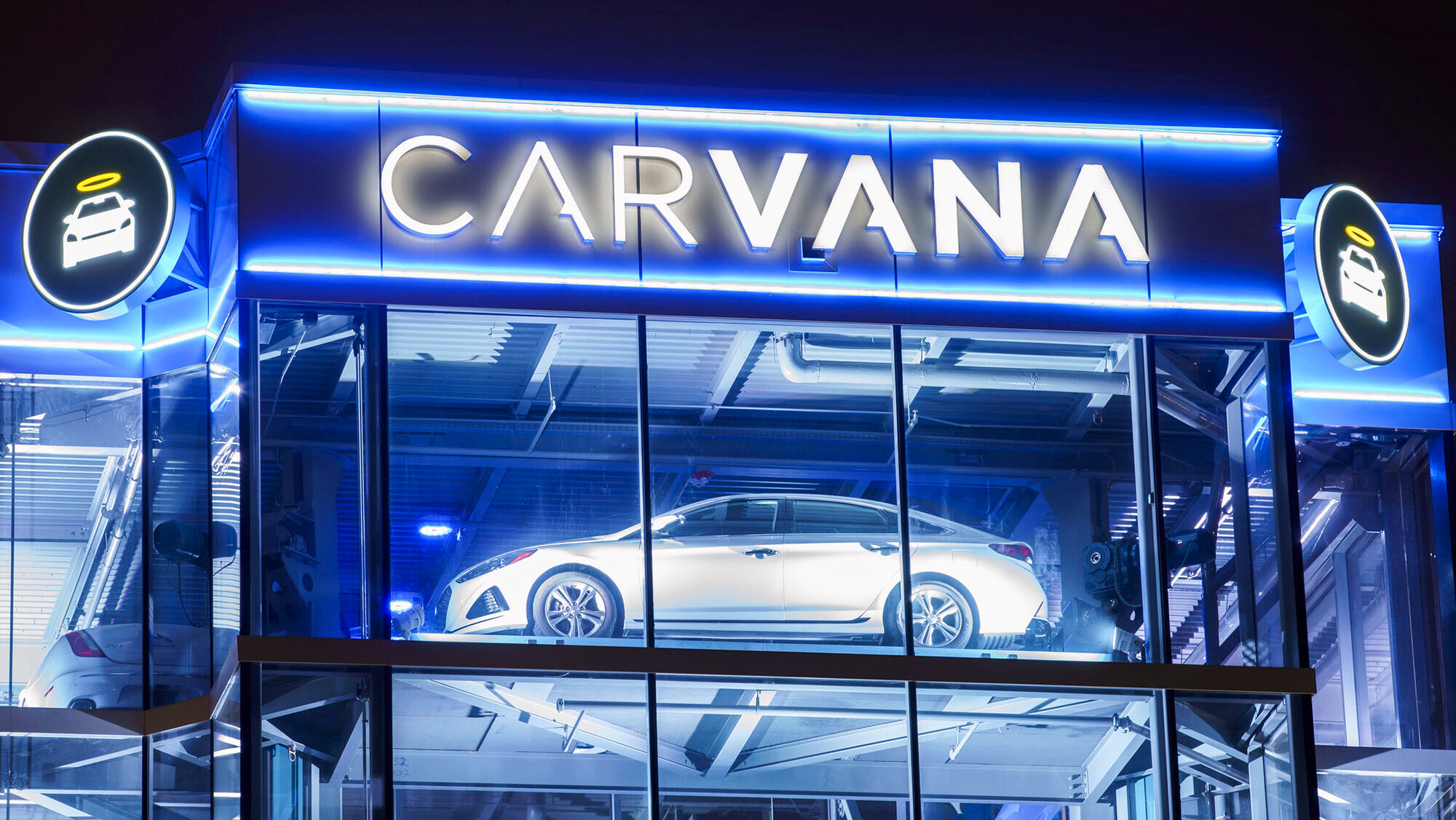 An illuminated Carvana glass tower is shown at night in Oak Brook, Illinois.