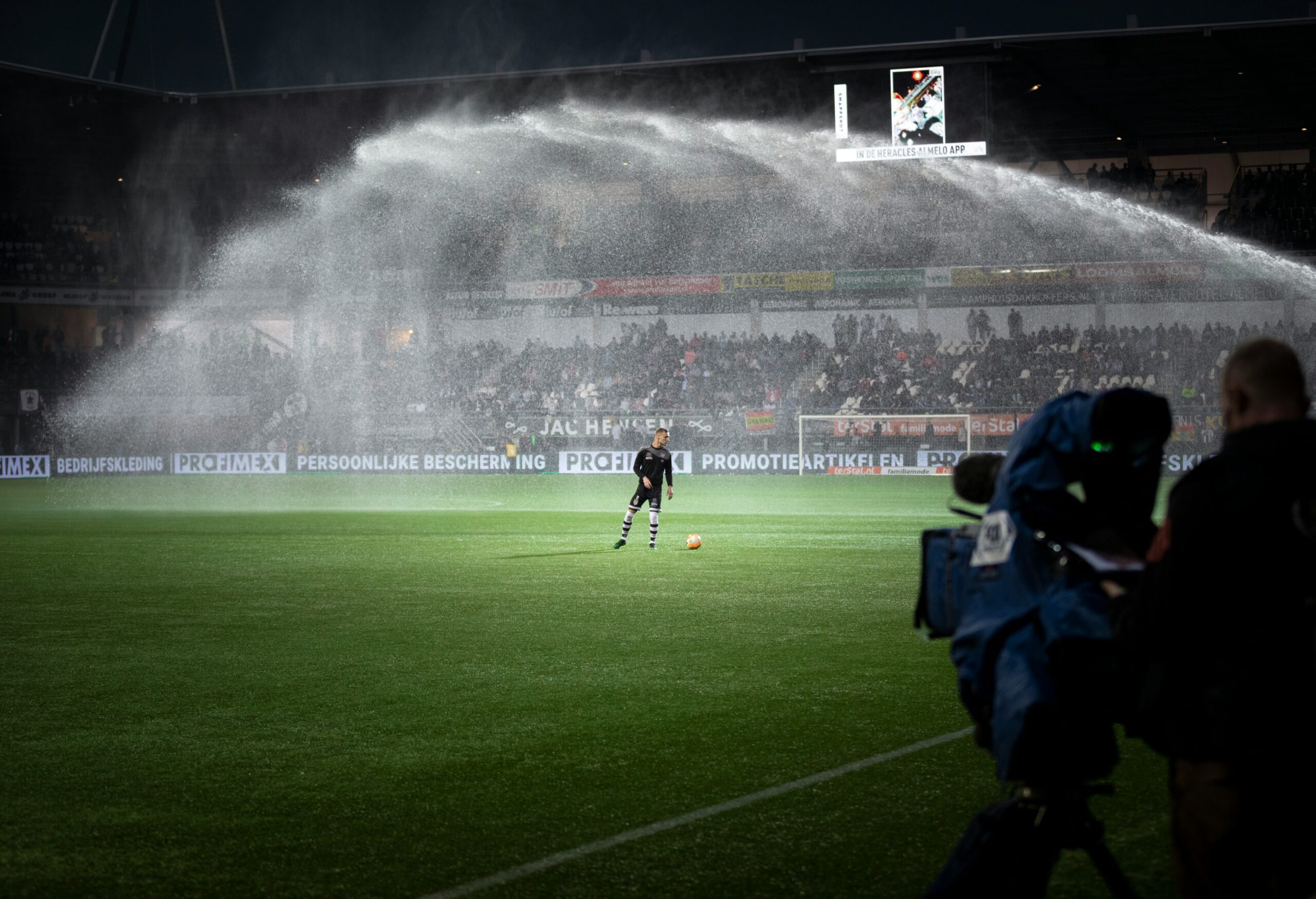 Football player warming up on the field in front of a large crowd in a stadium.
