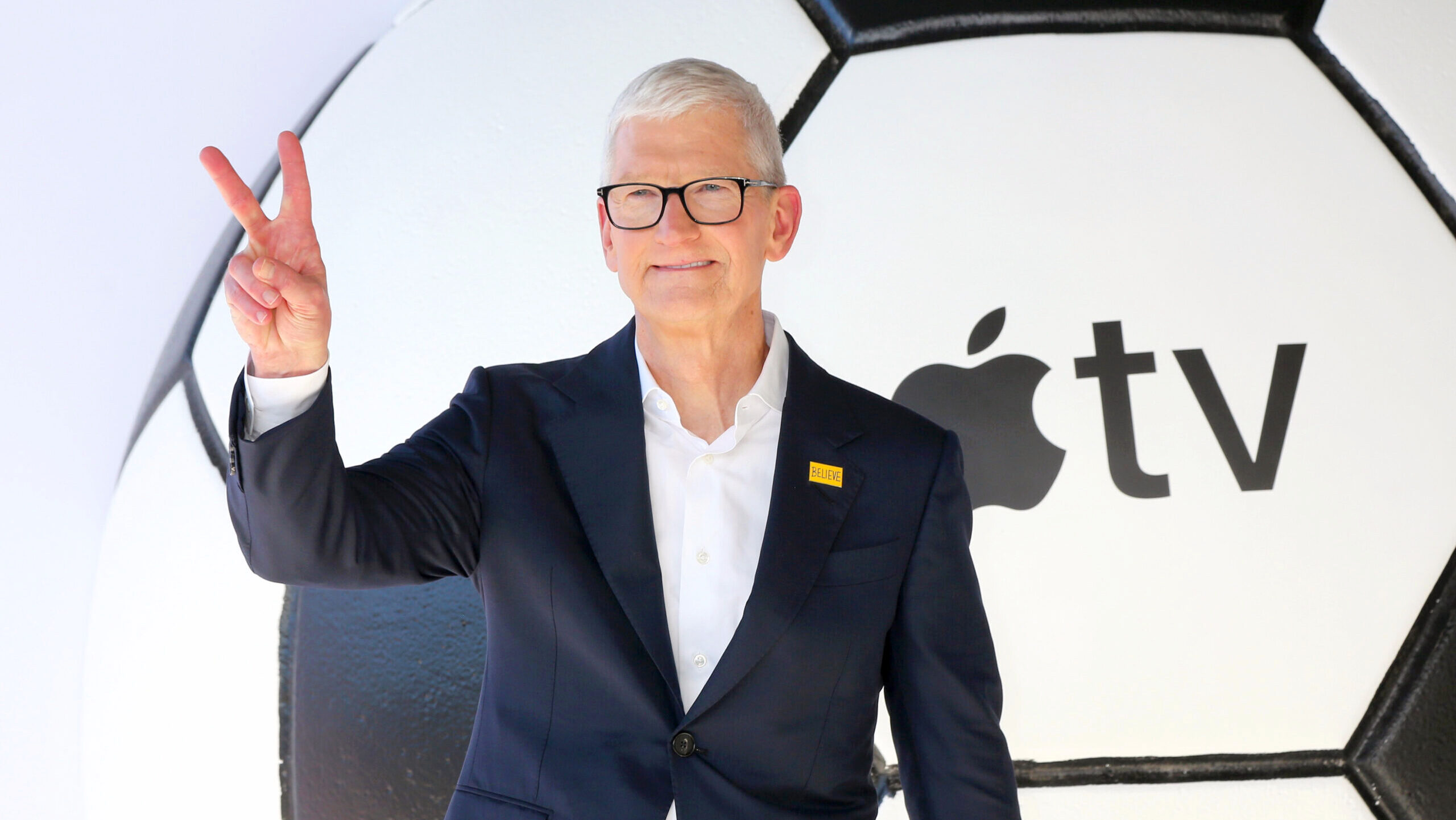 Apple CEO Tim Cook gives the peace sign in front of the Apple TV logo at the Academy Museum of Motion Pictures in Los Angeles.